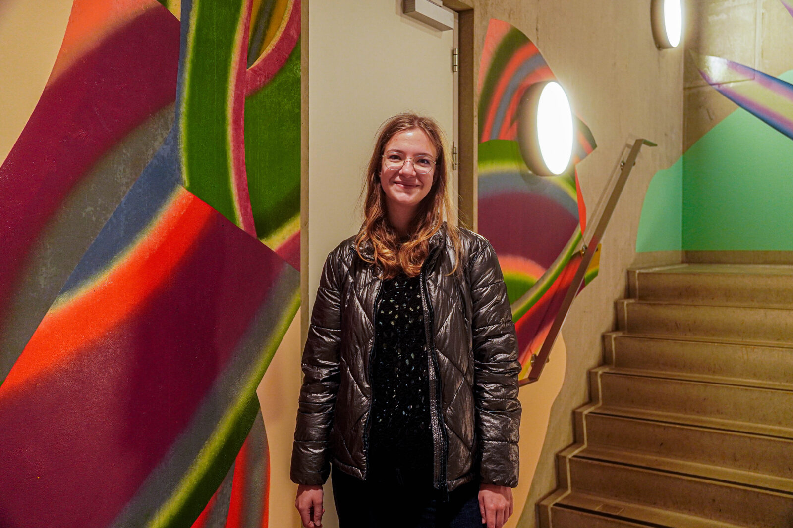 Student Beatrice poses in front of the mural in the Langeveld building.