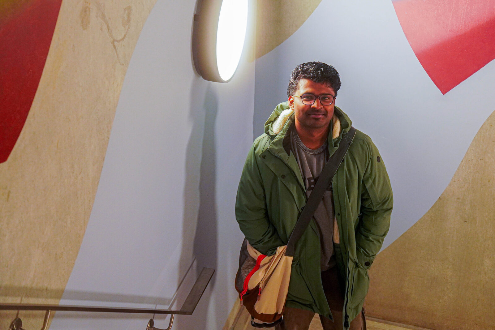 Student John poses in front of the mural in the Langeveld building.