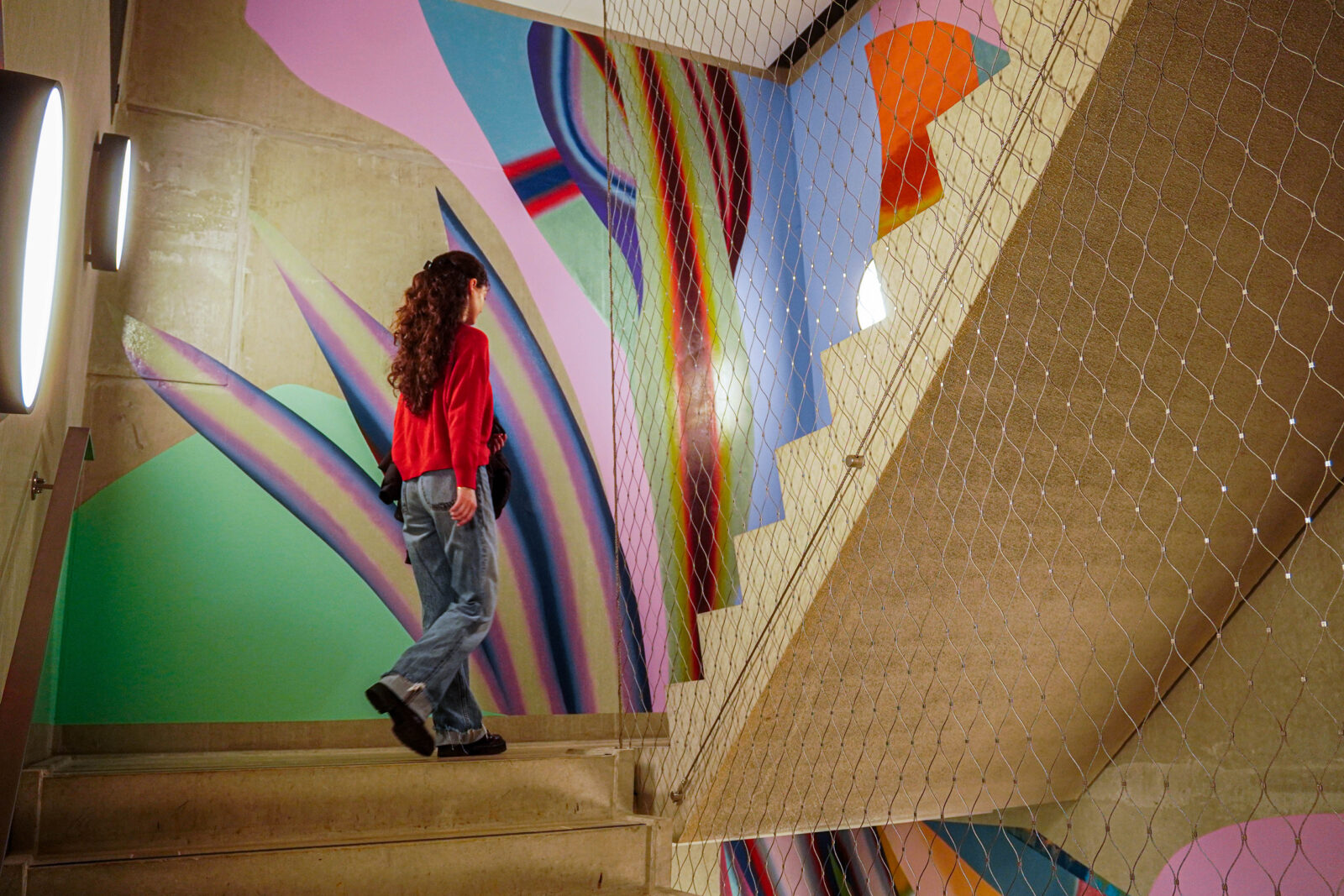 A student walks up the stairs past the colourful mural.