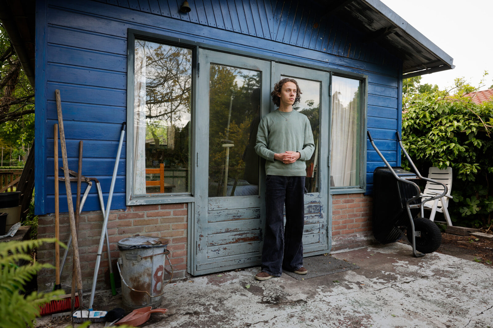 Finn van den Ijssel stands in front of the little blue house where the film Tuinhuis was shot