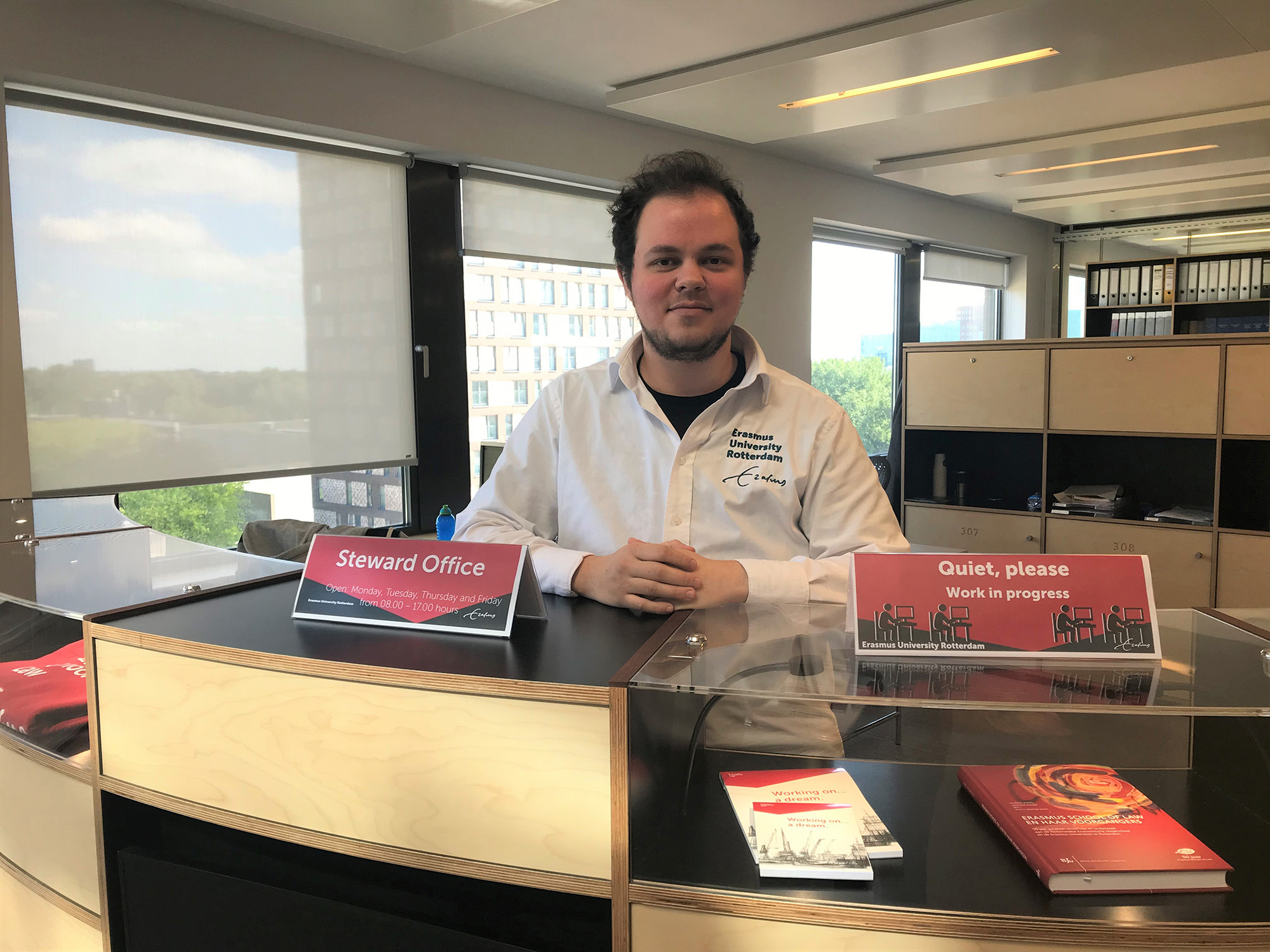 Dean van der Duin staat achter de balie om mensen te verwelkomen.