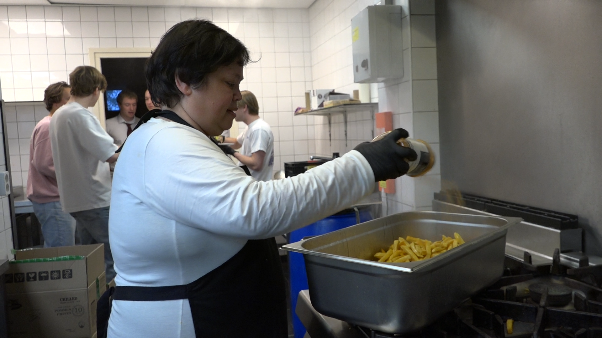 Kok Karin kruidt de patat voor het hoofdgerecht. Ze staat in de keuken van studentenvereniging Laurentius