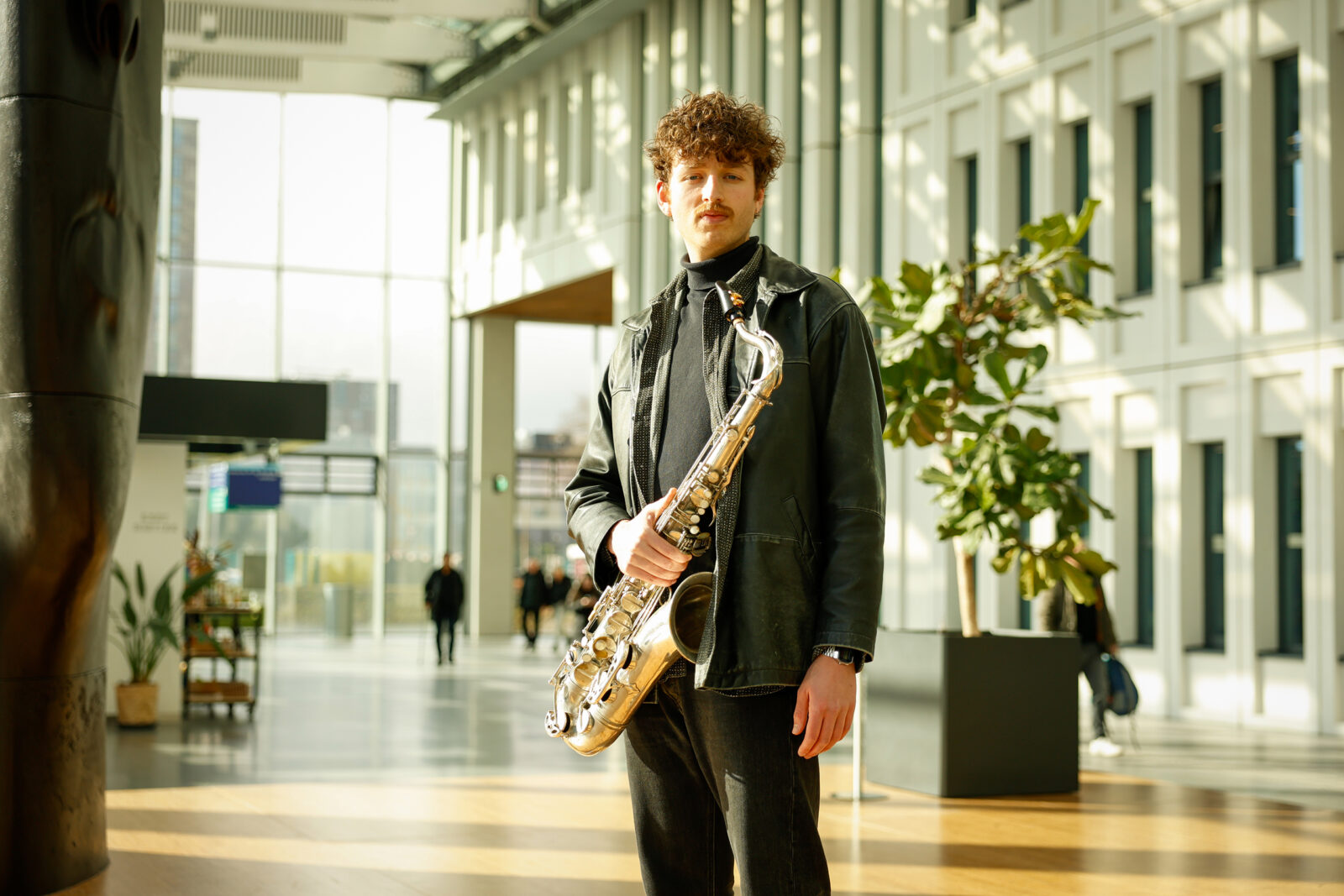 Daan Kluwer met saxofoon in de centrale hal van Erasmus MC.