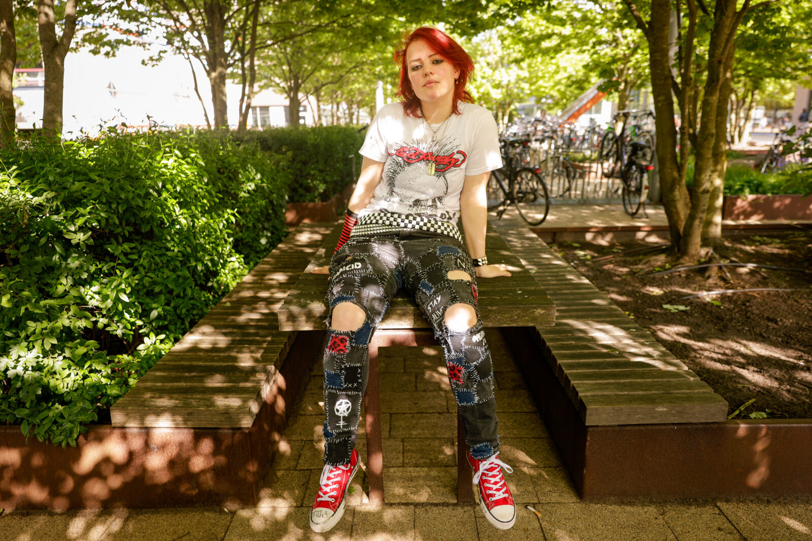 Jarelle poseert zittend op een tafel onder de bomen voor de rubriek Dresscode